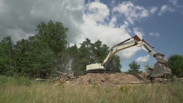 Kazıcı inşaat enkazı yığınının üzerinde duruyor ve kütükleri taşıyor — Stok video