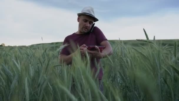 Man agronomist in hat holds tablet and ends talking on phone — Stock video