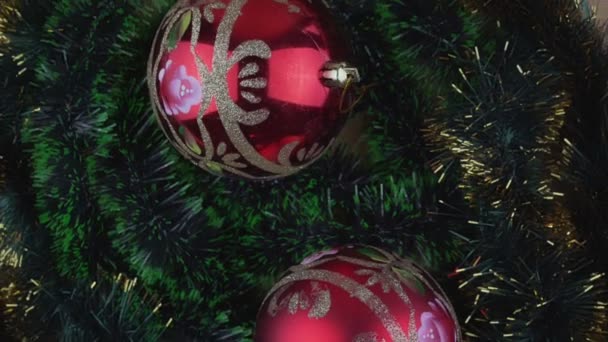 Twee grote rood gekleurde kerstballen draaien op groene klinkende achtergrond — Stockvideo