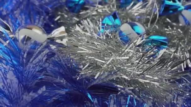 Glanzend blauw en wit snoep speelgoed draaien op multi gekleurde tinsel achtergrond — Stockvideo