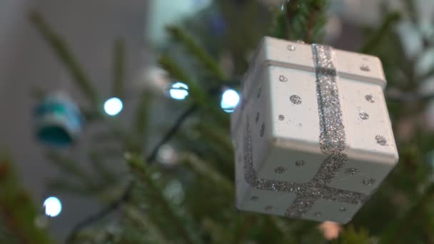 Silverfärgad presentask hängande på julgransgrenen hemma — Stockvideo