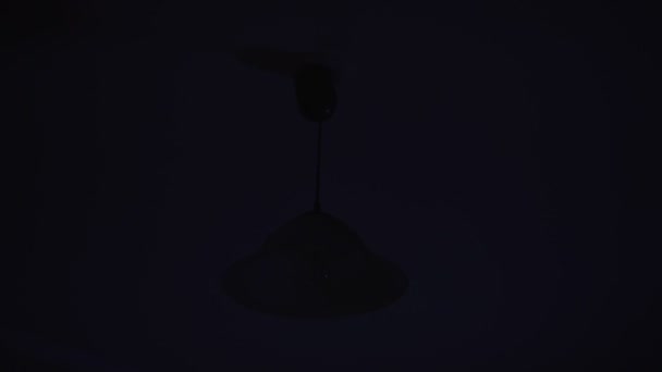 Fényes fény a mennyezeten lógó lámpa világít sötét szobában — Stock videók
