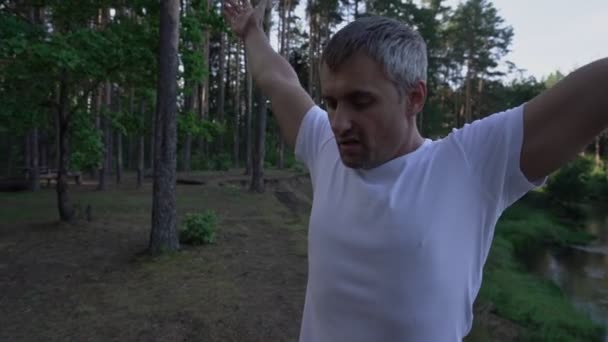 Człowiek robi ćwiczenia oddechowe w lesie w pobliżu rzeki — Wideo stockowe