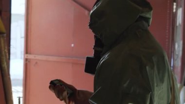 Yeşil savunma pelerinli siluetsiz kişi radyometre ile gösteriyor..