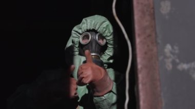 Koruyucu üniformalı bir adam havalı hareketler yapıyor ve el sallıyor.