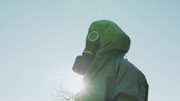Person wearing respirator standing outside against bright sunlight. — Stock Video