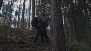 Baba ve oğlu, orman dağından turistik malzemelerle iniyorlar..