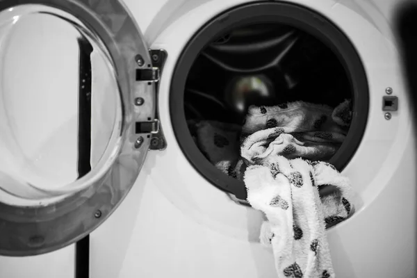 Vuile pyjama met grijze hartafdruk hangt aan de open deur van de wasmachine — Stockfoto