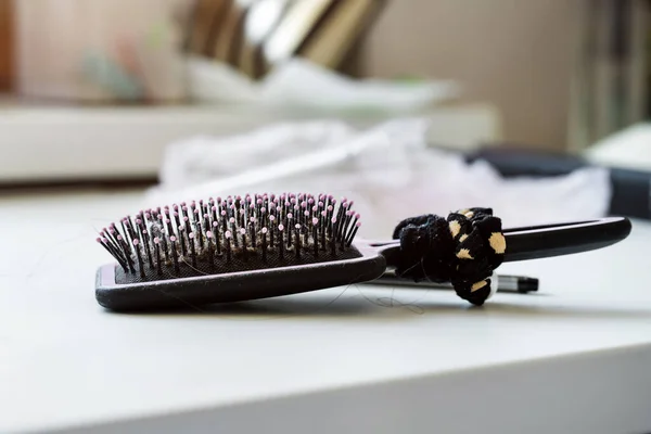 Hairbrush leží na stole s vlasovou stuhou pro culík ocas — Stock fotografie