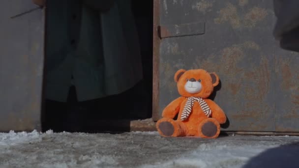 Man in antichemische kleding en gasmasker opent deur en tilt teddybeer — Stockvideo