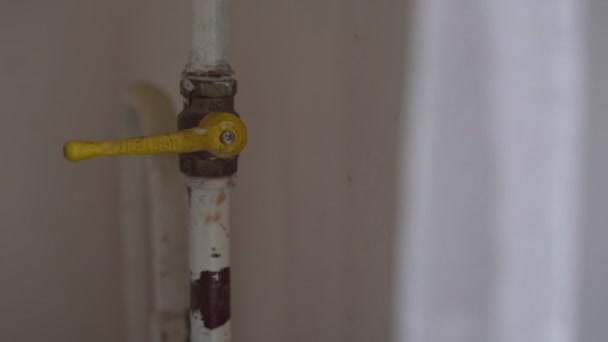 Мужская рука закрывает газовый клапан на старой ржавой металлической трубе на кухне — стоковое видео