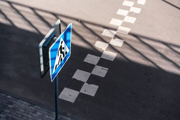 Panneau bleu et blanc fixé sur le poteau debout sur le trottoir près du passage piétonnier — Photo