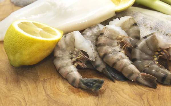 Marisco crudo, sepia, pescado y langostinos con limón a bordo —  Fotos de Stock