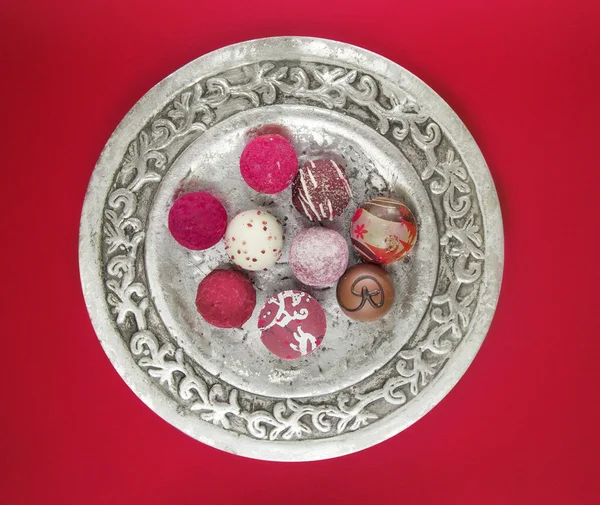 Silver plate with colorful pralines on red — Stock Photo, Image