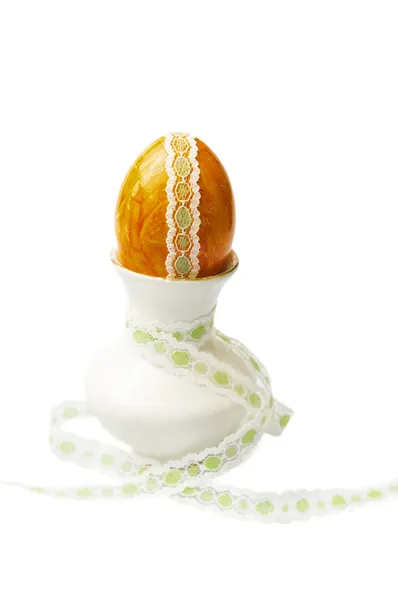 Orange easter deco egg with lace trimmings in mini vase on white background — Stock Photo, Image
