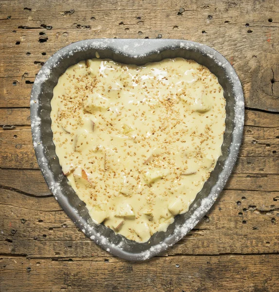 Pâte à biscuits dans un plat de cuisson en forme de coeur sur fond de table en bois, vue de dessus — Photo