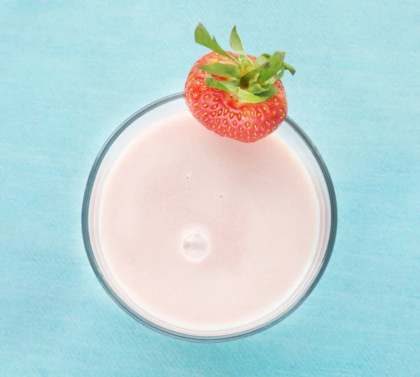 Růžové jahodový mléčný koktejl na modré tyrkysové, horní pohled — Stock fotografie