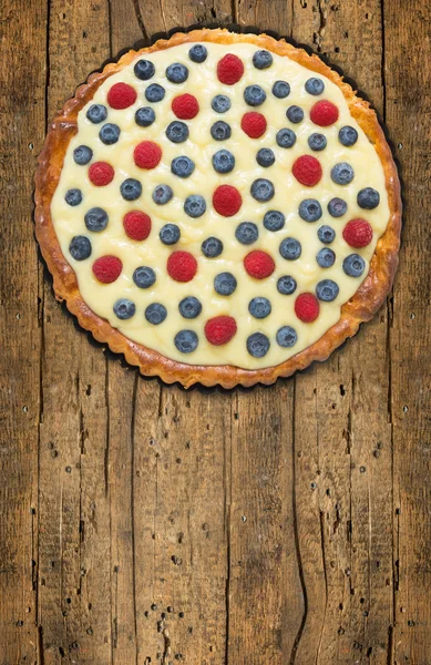 Tart with raspberries, blueberries, vanilla custard on old wood table — Stock Photo, Image