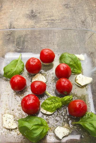 Tomatoes with basil and garlic in glass basin — Stock Photo, Image