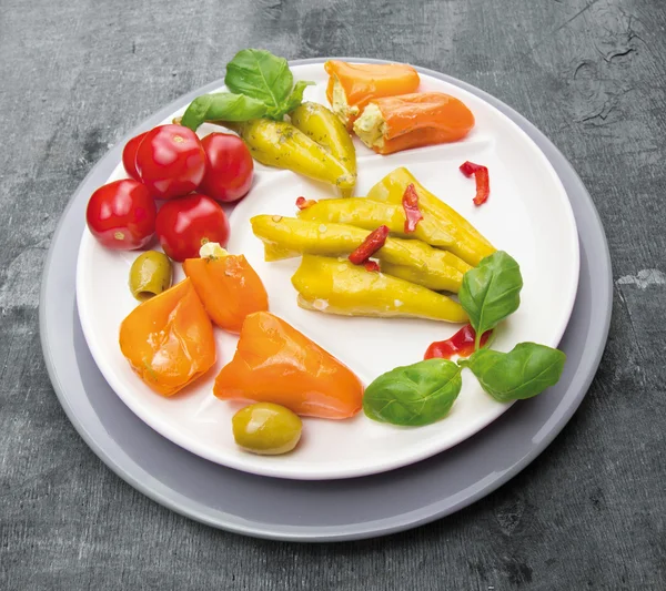 Antipasti vegetables , peppers with cream cheese , hot peppers , olives in plate on gray background — Stock Photo, Image