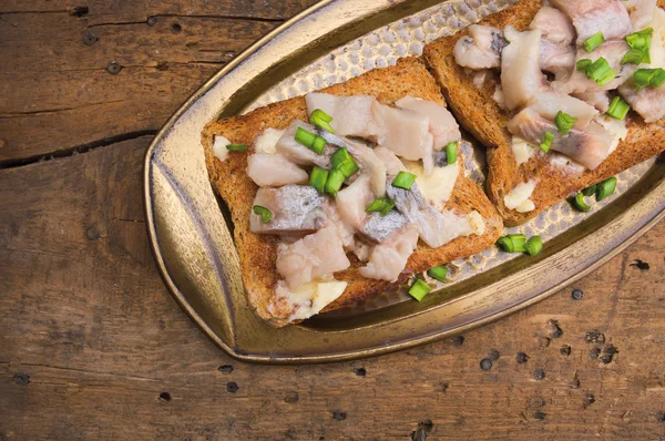 Toast med sill i antika bricka på gamla träbord — Stockfoto