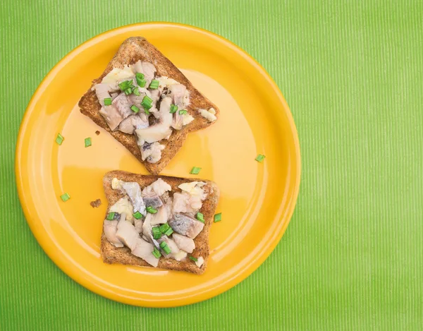 Sandwiches con sándwiches de arenque salado y cebollas verdes, sobre fondo verde — Foto de Stock