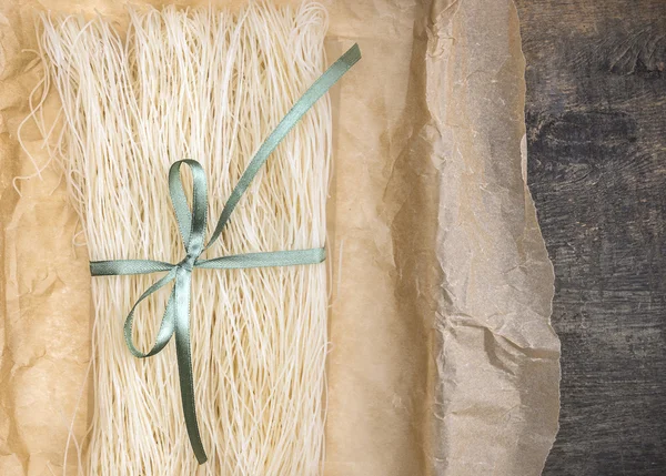 Chinese rice noodles,dry, in crumpled paper packaging with green ribbon