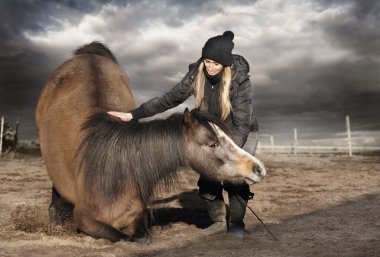 Woman hugging and kneeling horse paddock on autumn,trick training, cloudy weather clipart