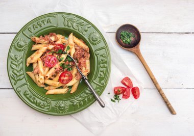 Yeşil plaka beyaz tahta üzerinde orkinos ve domates soslu makarna