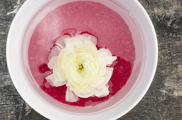 Flor de spa Ranunculus en agua roja sobre mesa de madera vieja —  Fotos de Stock