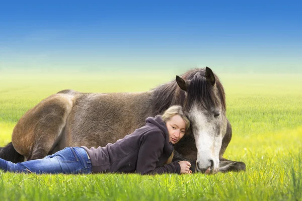 Mädchen und Pferd liegen und schlafen auf dem Feld, sonniger Sommertag, vor blauem Himmel, Freiheit, Reiterei lizenzfreie Stockbilder