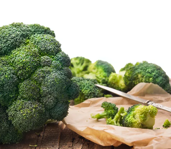 Broccoli head on  table in crumpled paper with knife,isolated — Stock Photo, Image