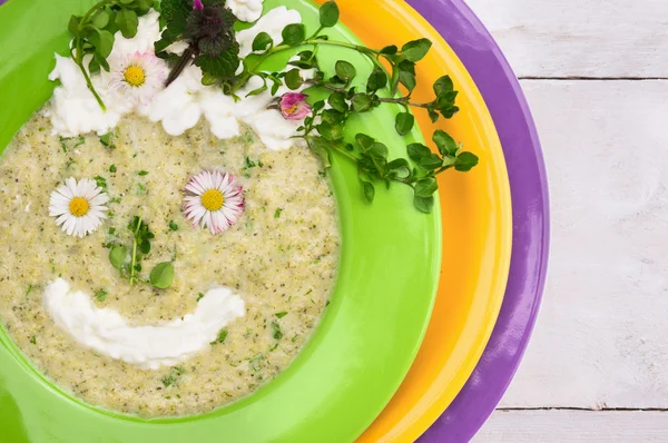 Spring green soup with wild herbs in colorful plates decorating smile little face — Stock Image Spring green soup with wild herbs in colorful plates decorating smile little face Royalty Free Stock Images