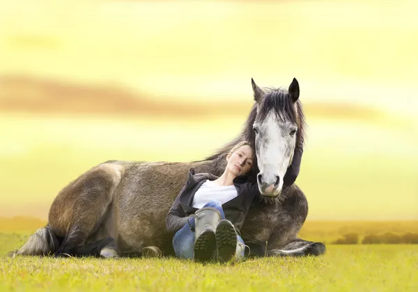 Hübsches Mädchen und graues arabisches Pferd liegen bei Sonnenuntergang auf der Sommerweide — Stockfoto