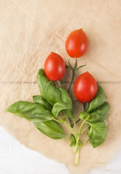 Bunch of  tomatoes and basil on brown paper — Stock Photo, Image