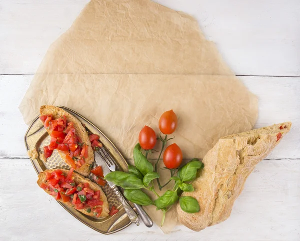 Bruschetta z ciabatta, pomidorami i bazylia na papierze — Zdjęcie stockowe