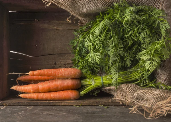 Carrots bunch with leaves in old wooden box — Stockfoto