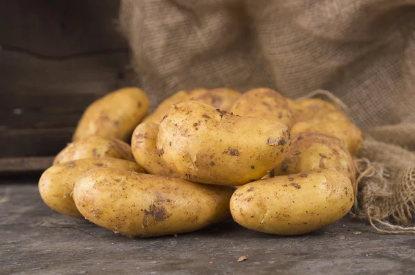 Fresh potatoes on  dark  old wooden background — Stock Photo, Image