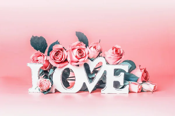 トレンディなリビングサンゴの色の背景に言葉の愛とパステルピンクのバラと抽象的な愛の概念 創造的なロマンチックなレイアウト 結婚式のカード スペースのコピー — ストック写真