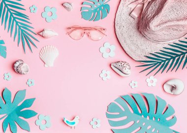 Yaz geçmişi. Pastel pembe kadın aksesuarları: güneş gözlüğü ile hasır şapka, deniz kabukları ve pembe arka plan üzerinde turkuaz mavitropikal yaprakları, üst görünümü. Yaz tatili konsepti. Tropikal tatil .
