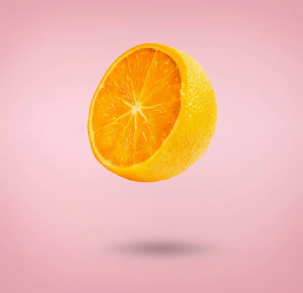 Media Fruta Naranja Volando Sobre Fondo Rosa Con Sombra Concepto — Foto de Stock