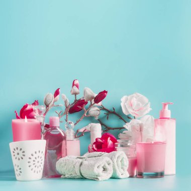 Havlular, çiçekler, mumlar ve vücut bakım kozmetikleri açık mavi renkte, fotokopi alanı olan üst görünümü olan pembe kaplıca seti. Güzellik konsepti