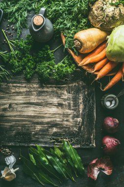 Kök sebze malzemeleri koyu mutfak masasının arka planında otlar ve baharatlarla, üst manzara. Uzayı kopyala Vejetaryen yemek ve yeme konsepti. Sağlıklı yemek.