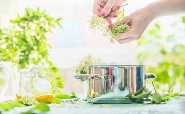 Dişi eller yemek tenceresi, limon ve şeker ile masada yaşlı çiçekleri hazırlar. Ev yapımı Elderflower şurubu ya da reçel yapımı. Tarifleriniz için alanı kopyalayın. Sağlıklı mevsimlik doğal yiyecekler