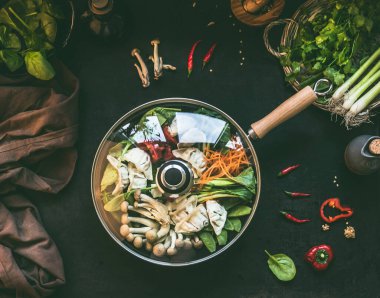 Vejetaryen Kore usulü tava, sebzeli sıcak tencere ve koyu kırsal mutfak masasında hamur tatlısı, malzemelerle birlikte, üst manzara. Boşluğu kopyala.