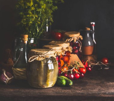 Jars with variety of traditional preserved fermented farm organic seasonal vegetables and fruits  on dark rustic background. Autumn canning. Conservation of harvest. Healthy homemade food