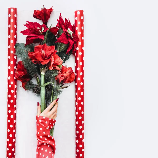 圣诞花朵布置 在白色桌面上的包装纸上 身穿红色衬衫 手持冬季花朵的女性手与Amaryllis Poinsettia和冷杉的枝条束在一起 顶部视图 复制空间 — 图库照片