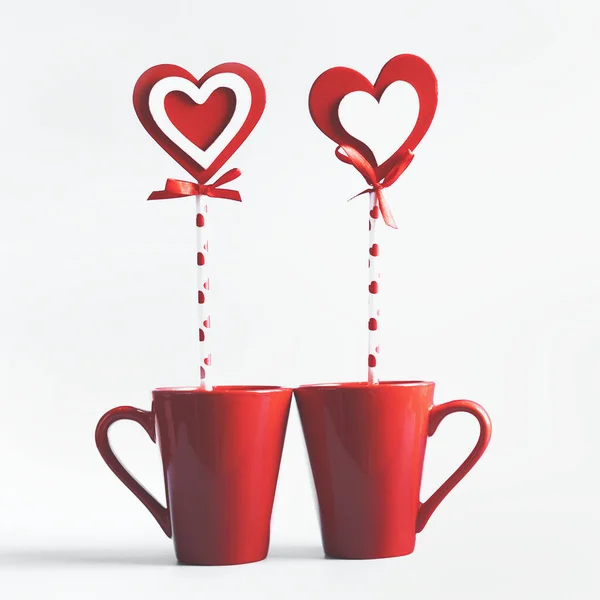白い背景にハートのロリポップが立っている2つの赤いマグカップ 愛とバレンタインデーのコンセプトの宣言 — ストック写真