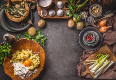 Patates hamuru hazırlayan köylü yemekleri. Tahta kasede yumurta ve un ile patates püresi. Lezzetli ev yemekleri için organik malzemelerle dolu karanlık mutfak masası. Çerçeve. Üst görünüm.