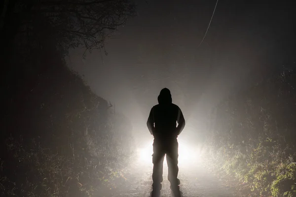 脅迫図は 車のヘッドライトの前に立っている 田舎道で 霧の多い冬の夜に — ストック写真